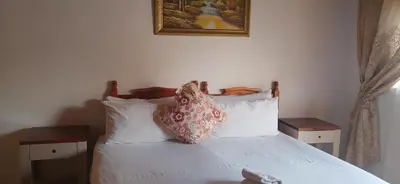 a bedroom with a white bed with a pillow on it at Hilo guesthouse in Witbank