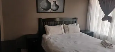 a bedroom with a bed with white sheets and pillows at Hilo guesthouse in Witbank