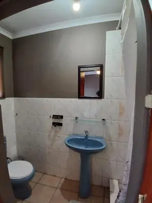 a bathroom with a blue sink and a toilet at Hilo guesthouse in Witbank
