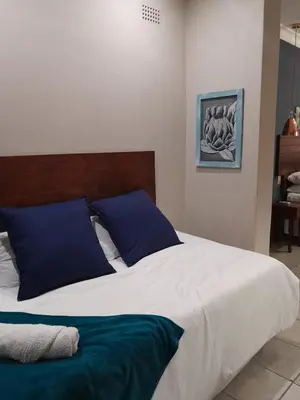 a bedroom with a large bed with blue pillows at Ebenezer Self Catering in Groblersdal