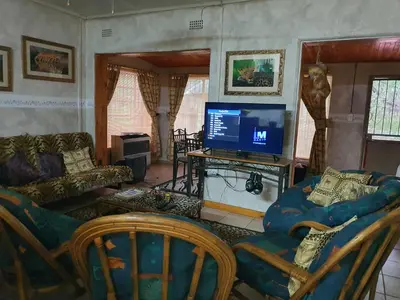 a living room with a flat screen tv and chairs at Matumi Self Catering in Marloth Park