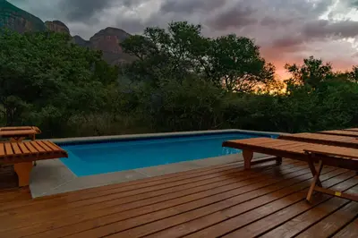 a deck with a swimming pool and two picnic tables at Cape Vulture Lodge in Hoedspruit