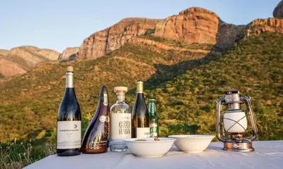 four bottles of wine sitting on a table with mountains in the background at Cape Vulture Lodge in Hoedspruit