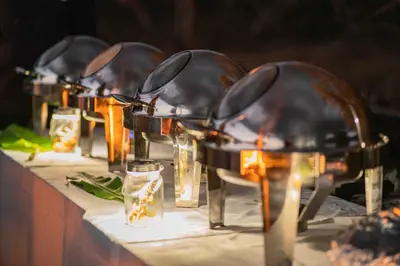 a row of tables with silver plates and glasses at Cape Vulture Lodge in Hoedspruit