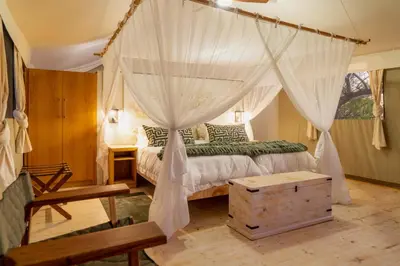 a bedroom with a canopy bed with a wooden floor at Cape Vulture Lodge in Hoedspruit