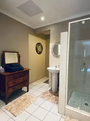 a bathroom with a sink and a shower and a mirror at The Cottage at 152 in Centurion
