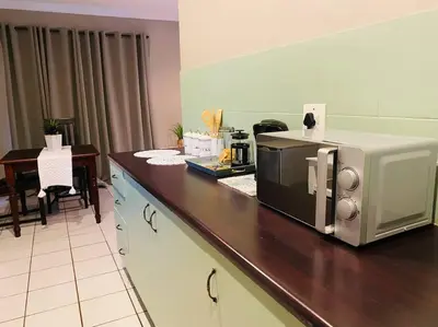a kitchen with a microwave on a counter with a table at The Cottage at 152 in Centurion