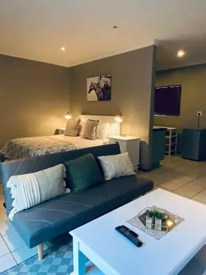 a living room with a couch and a bed at The Cottage at 152 in Centurion