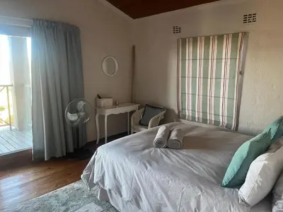 a bedroom with a bed and a desk with a fan at Le Bella Dons in Graskop