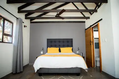 a bedroom with a bed with yellow pillows and a ceiling at Rock House at Benlize in Hartbeespoort