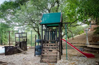 a playground with a slide and a swing set at Rock House at Benlize in Hartbeespoort