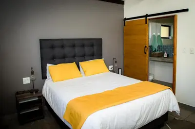 a bedroom with a large bed with two yellow pillows at Rock House at Benlize in Hartbeespoort