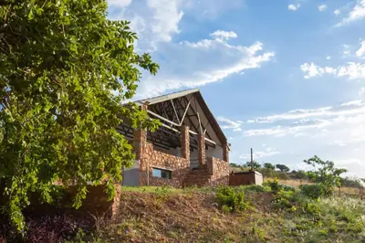 a brick house on a hill with a tree at Rock House at Benlize in Hartbeespoort