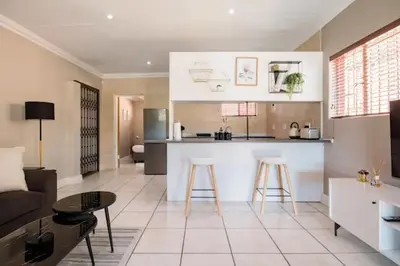 a kitchen and living room with a couch and a counter at Beautiful and Modern apartment close to Menlyn in Pretoria