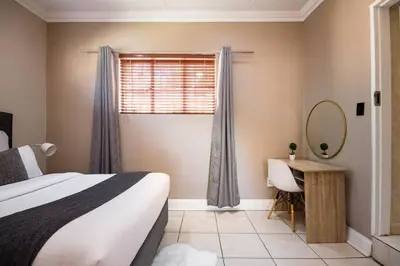a bedroom with a bed and a mirror and a window at Beautiful and Modern apartment close to Menlyn in Pretoria