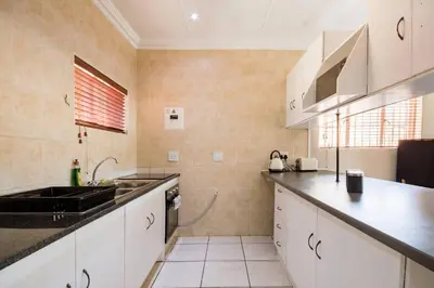 a kitchen with white cabinets and a sink at Beautiful and Modern apartment close to Menlyn in Pretoria