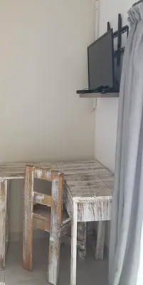 a wooden table with a chair and a television on a shelf at Lime Court two in Pretoria