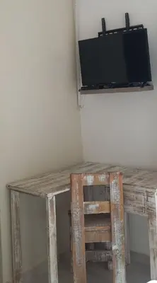 a wooden table with a chair and a tv on a wall at Lime Court two in Pretoria