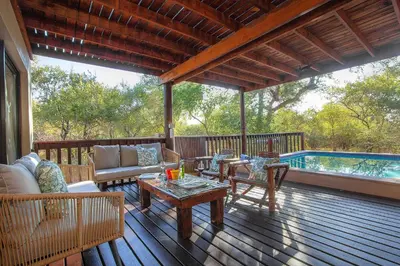 a porch with a couch and chairs on a deck at Call of the Fish Eagle Self-catering Holiday Home with solar in Marloth Park