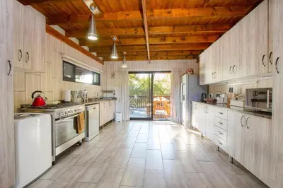 a large kitchen with white appliances and wooden ceilings at Call of the Fish Eagle Self-catering Holiday Home with solar in Marloth Park