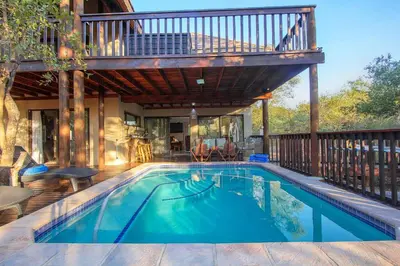 a house with a swimming pool with a deck at Call of the Fish Eagle Self-catering Holiday Home with solar in Marloth Park