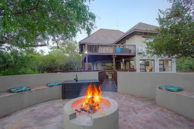 a fire pit in a yard in front of a house at Call of the Fish Eagle Self-catering Holiday Home with solar in Marloth Park