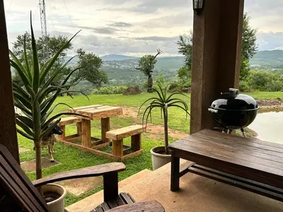 a porch with a bench and a grill and a table at Hazyview Accommodation, Bon Repose Cottage 2 in Hazyview