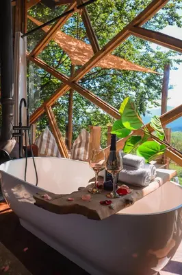 a bath tub with two wine glasses and a table at Quaint Luxury Villas in Graskop