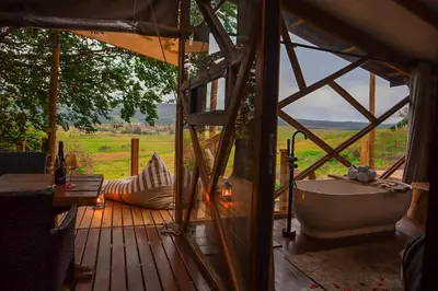a tub on a wooden deck with a view of a field at Quaint Luxury Villas in Graskop