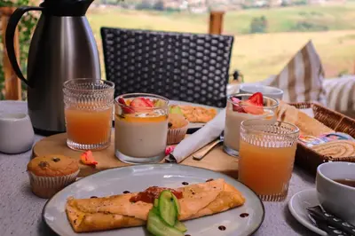 a table with a plate of food and glasses of orange juice at Quaint Luxury Villas in Graskop