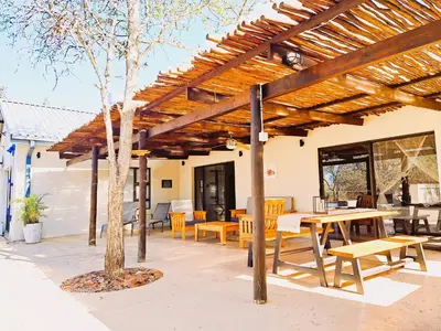 a wooden pergola with a picnic table and benches at Ostrich Hide in Marloth Park