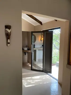 a room with a door open to a kitchen at Ostrich Hide in Marloth Park