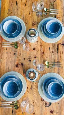 a table with blue and white plates and wine glasses at UmnDeni Africa in Hoedspruit