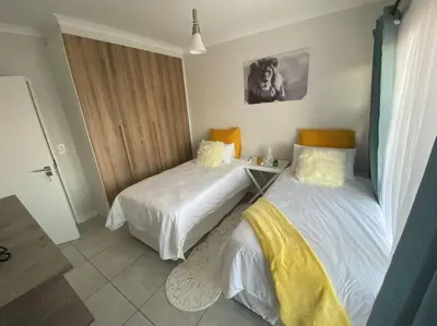 a bedroom with two beds and a table in it at TK’s Penthouse - The Blyde in Pretoria