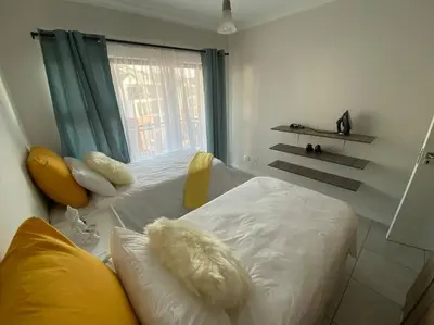 a bedroom with a bed with white sheets and a window at TK’s Penthouse - The Blyde in Pretoria