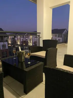 a balcony with a table and two glasses of wine at TK’s Penthouse - The Blyde in Pretoria