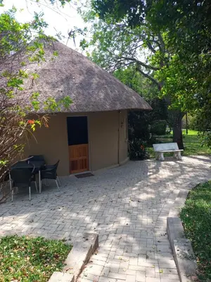 a building with a thatch roof and a table and a bench at Crocodile Nest B&B in Nelspruit