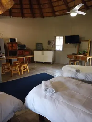 a room with three beds and a table and a television at Crocodile Nest B&B in Nelspruit