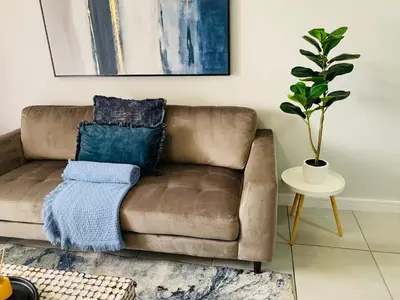 a brown couch in a living room with a potted plant at The Blyde -Ender137 in Pretoria