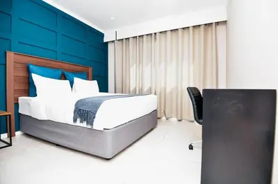 a bedroom with a bed and a blue wall at Unit 508 at Menlyn Place in Pretoria