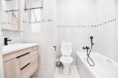 a white bathroom with a toilet and a bath tub at Unit 508 at Menlyn Place in Pretoria