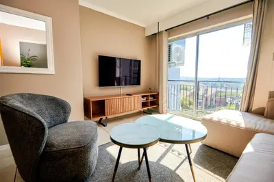 a living room with a couch and a tv at Unit 508 at Menlyn Place in Pretoria