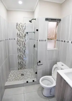 a white bathroom with a toilet and a shower at Unit 508 at Menlyn Place in Pretoria