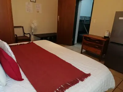 a bedroom with a bed with a red blanket on it at Ebenhaeser overnight accomodation in Bela-Bela