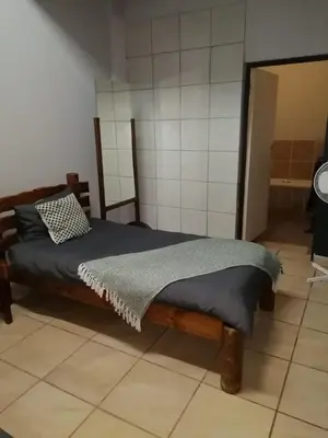a bedroom with a wooden bed with a blanket at Ebenhaeser overnight accomodation in Bela-Bela