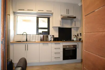 a kitchen with white cabinets and a sink and a window at Locust Retreat in Marloth Park in Marloth Park
