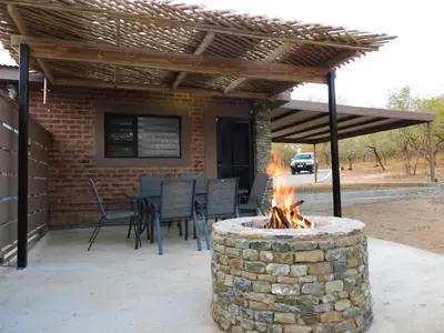 a patio with a fire pit in front of a house at Locust Retreat in Marloth Park in Marloth Park