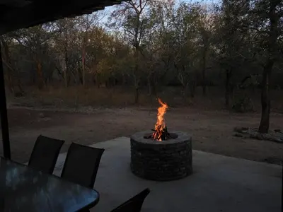 a fire pit sitting on a patio with chairs at Locust Retreat in Marloth Park in Marloth Park