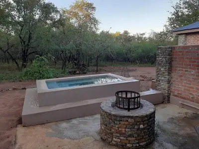 a swimming pool in a yard with a brick building at Locust Retreat in Marloth Park in Marloth Park