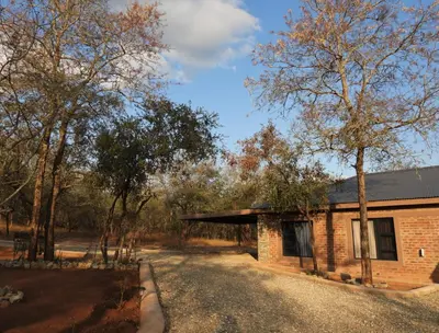 a brick house in the middle of a forest at Locust Retreat in Marloth Park in Marloth Park
